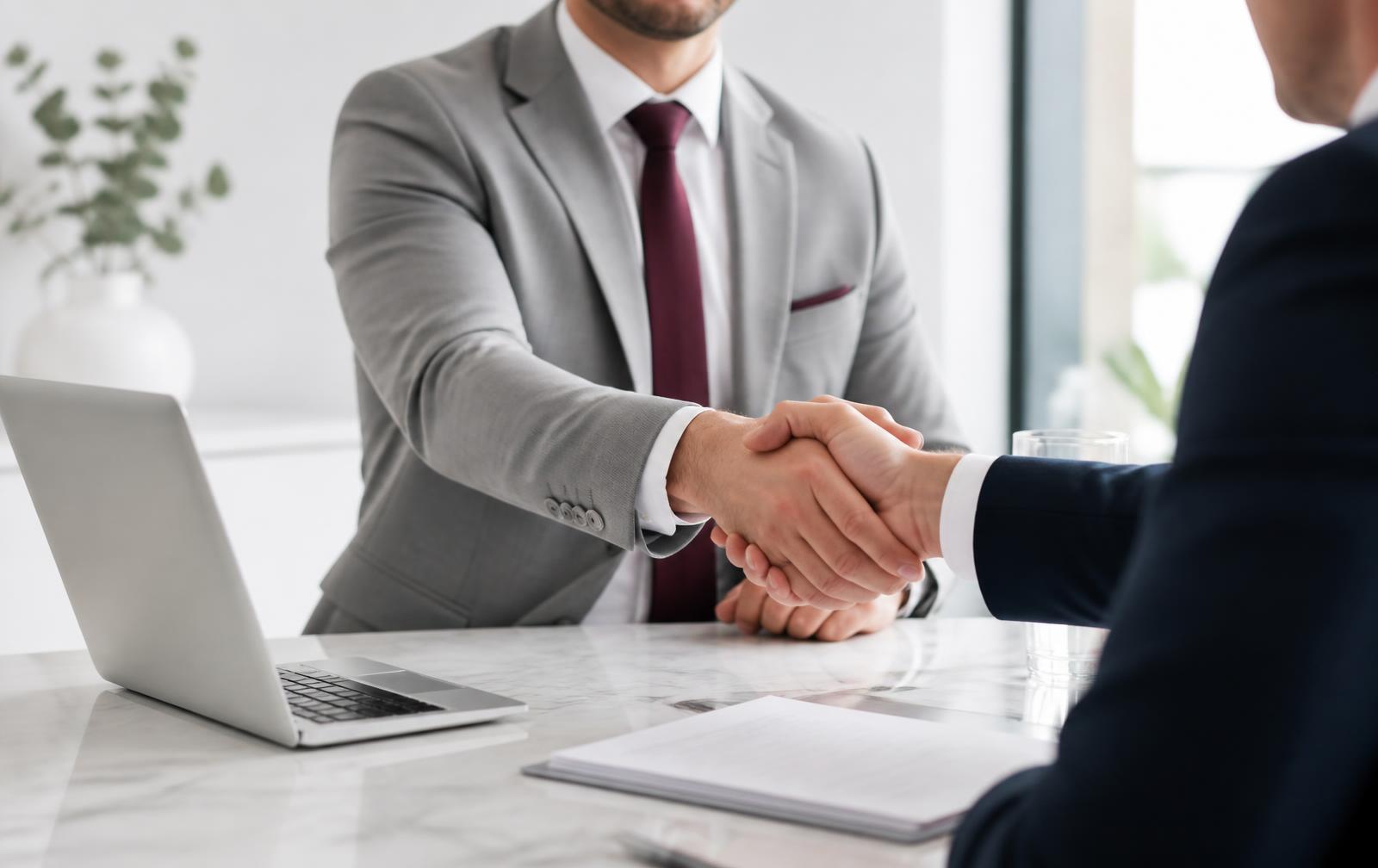 Aperto de mãos entre executivos fechando uma parceria comercial em ambiente corporativo